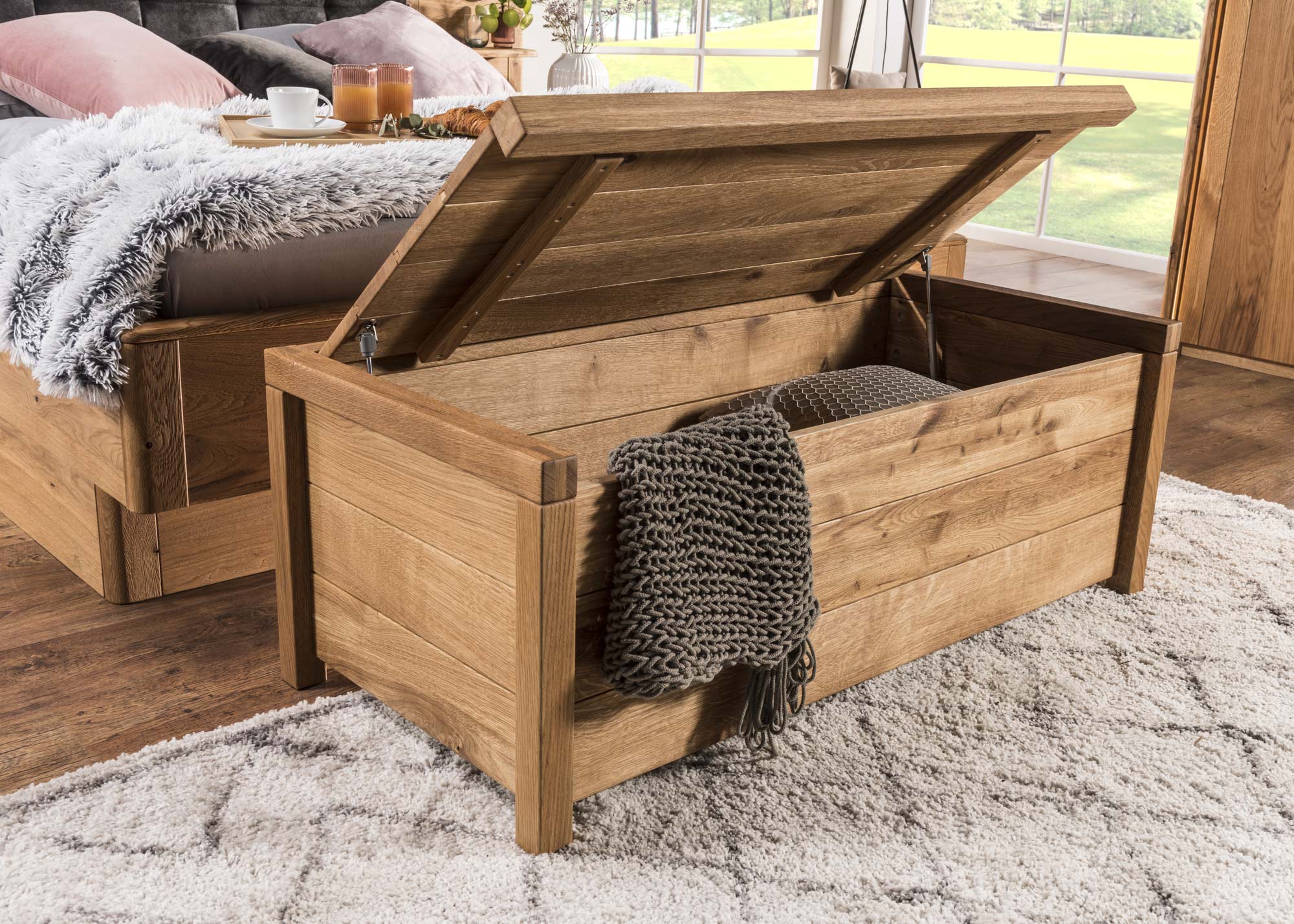 Otwarte wieko skrzyni z drewnianym wnętrzem i kocem