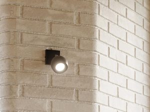 Miniaturka 11 - Biały kinkiet LED z okrągłą głowicą zamontowany na cegle