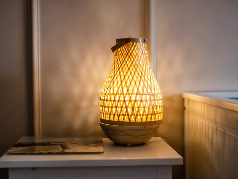 Pleciona lampa rattanowa na stoliku nocnym w stylu boho