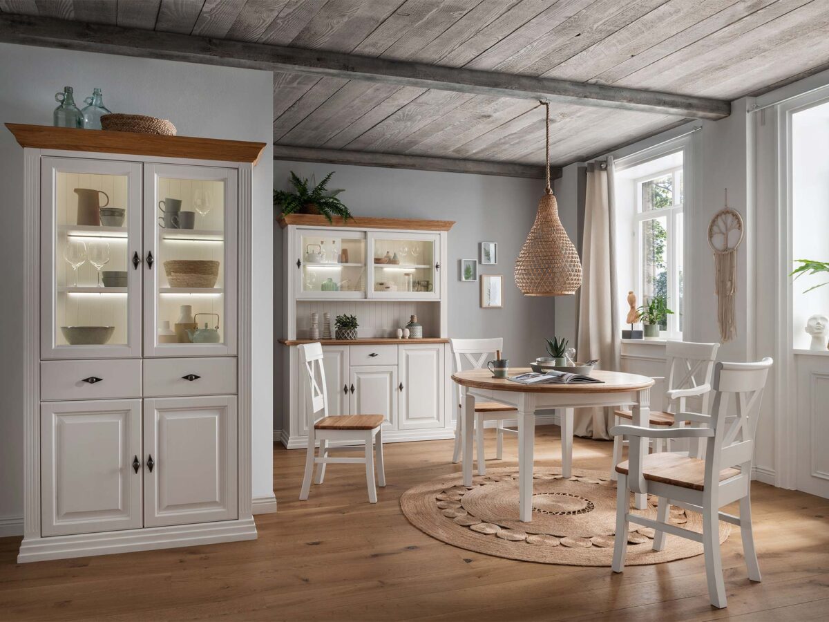 Białe witryny i okrągły stół w prowansalskiej jadalni