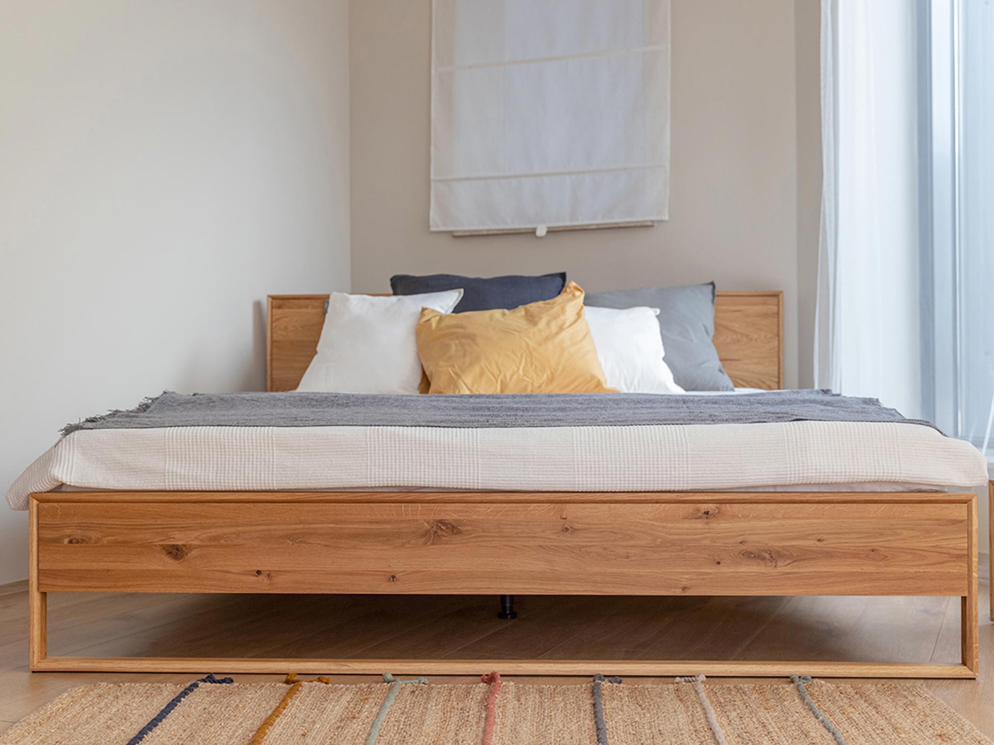 Naturalne łóżko z drewna z dekoracyjną poduszką w aranżacji