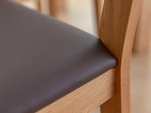 Miniaturka 10 - Detal siedziska tapicerowanego krzesła z dębowymi nogami