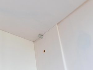 Miniaturka 1 - Wnętrze szafki z białą płytą i śrubami montażowymi