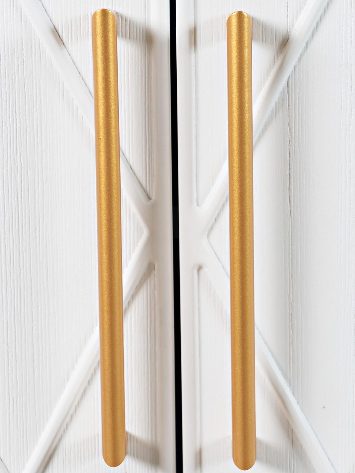 Detal złotych uchwytów na białych frontach komody Detal złotych uchwytów na białych frontach komody