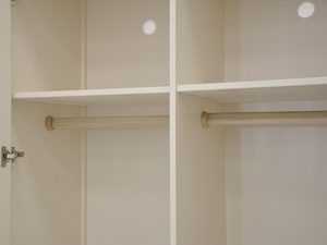 Miniaturka 2 - Wnętrze szafy drewnianej z drążkami na ubrania w kolorze ecru