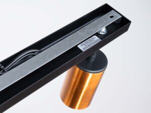 Miniaturka 3 - Wnętrze czarnej listwy montażowej plafonu z okablowaniem i złotym reflektorem