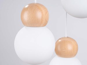 Miniaturka 4 - Zbliżenie na drewniane kule i białe szklane klosze lampy