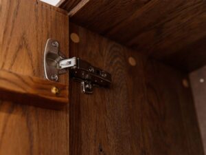 Miniaturka 7 - Detal zawiasu drzwi komody tabacco z usłojeniem drewna zbliżenie