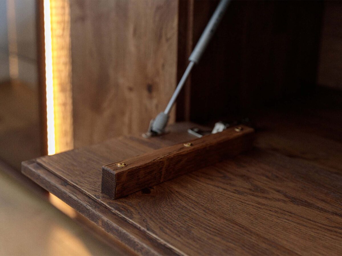 Detal klapy komody tabacco z uchwytem siłownikiem i podświetleniem LED Detal klapy komody tabacco z uchwytem siłownikiem i podświetleniem LED