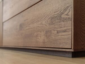 Miniaturka 6 - Detal cokołu i frontu szuflad komody tabacco z usłojeniem dębu