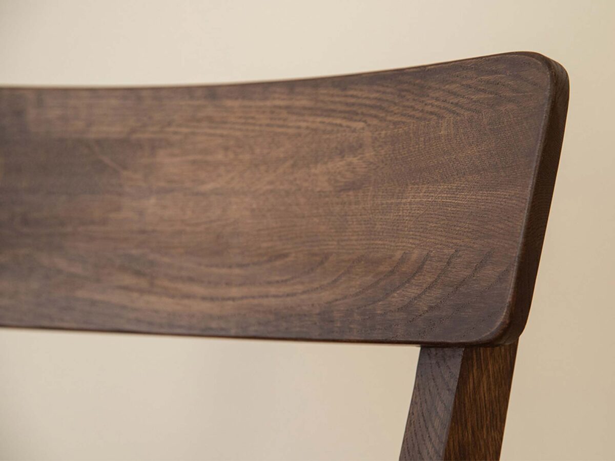 Detal oparcia krzesła dębowego ciemnego z widocznymi słojami drewna Detal oparcia krzesła dębowego ciemnego z widocznymi słojami drewna
