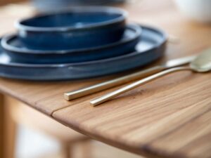 Miniaturka 18 - Detal krawędzi blatu stołu dębowego z granatową zastawą zbliżenie