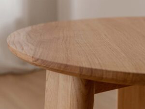 Miniaturka 5 - Detal blatu dębowego stolika kawowego z widocznym usłojeniem i nogą