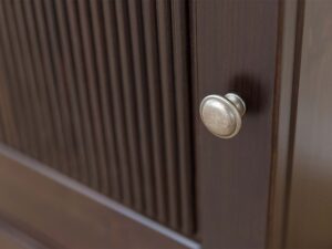 Miniaturka 2 - Detal gałki drzwi komody trójdrzwiowej drewnianej ciemnobrązowej z ryflowanym panelem