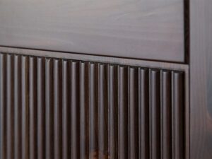 Miniaturka 1 - Detal ryflowanego frontu drzwi szafy czterodrzwiowej drewnianej ciemnobrązowej zbliżenie