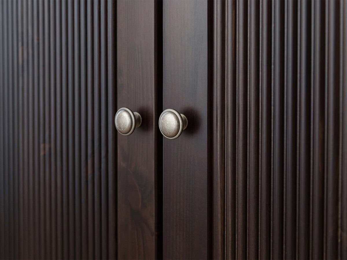 Detal narożnika szafy trójdrzwiowej drewnianej ciemnobrązowej z usłojeniem