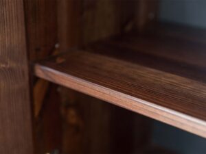 Miniaturka 1 - Detal półki drewnianej ciemnobrązowej z naturalnym usłojeniem w szafie zbliżenie