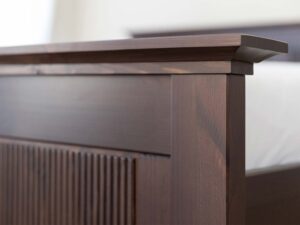 Miniaturka 2 - Detal górnego narożnika ramy łóżka drewnianego ciemnobrązowego zbliżenie