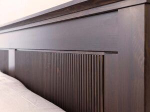 Miniaturka 6 - Detal zagłówka łóżka drewnianego ciemnobrązowego z ryflowanymi panelami zbliżenie