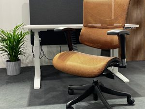 Miniaturka 1 - Pomarańczowy fotel biurowy ergonomiczny siatkowy przy biurku w aranżacji