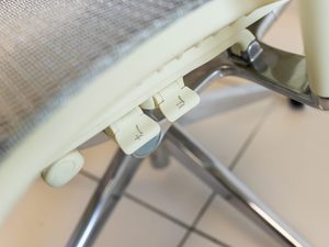 Miniaturka 3 - Biały fotel biurowy detal mechanizmu regulacji pod siedziskiem zbliżenie