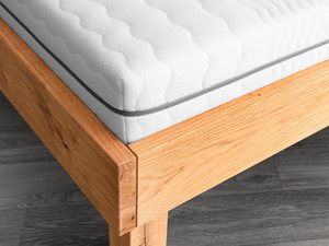 Miniaturka 4 - Łóżko dębowe detal narożnika ramy i masywnej nogi usłojenie drewna zbliżenie