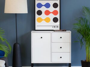 Miniaturka 3 - Komoda Linvero w białym wariancie we wnętrzu z roślinami i lampą