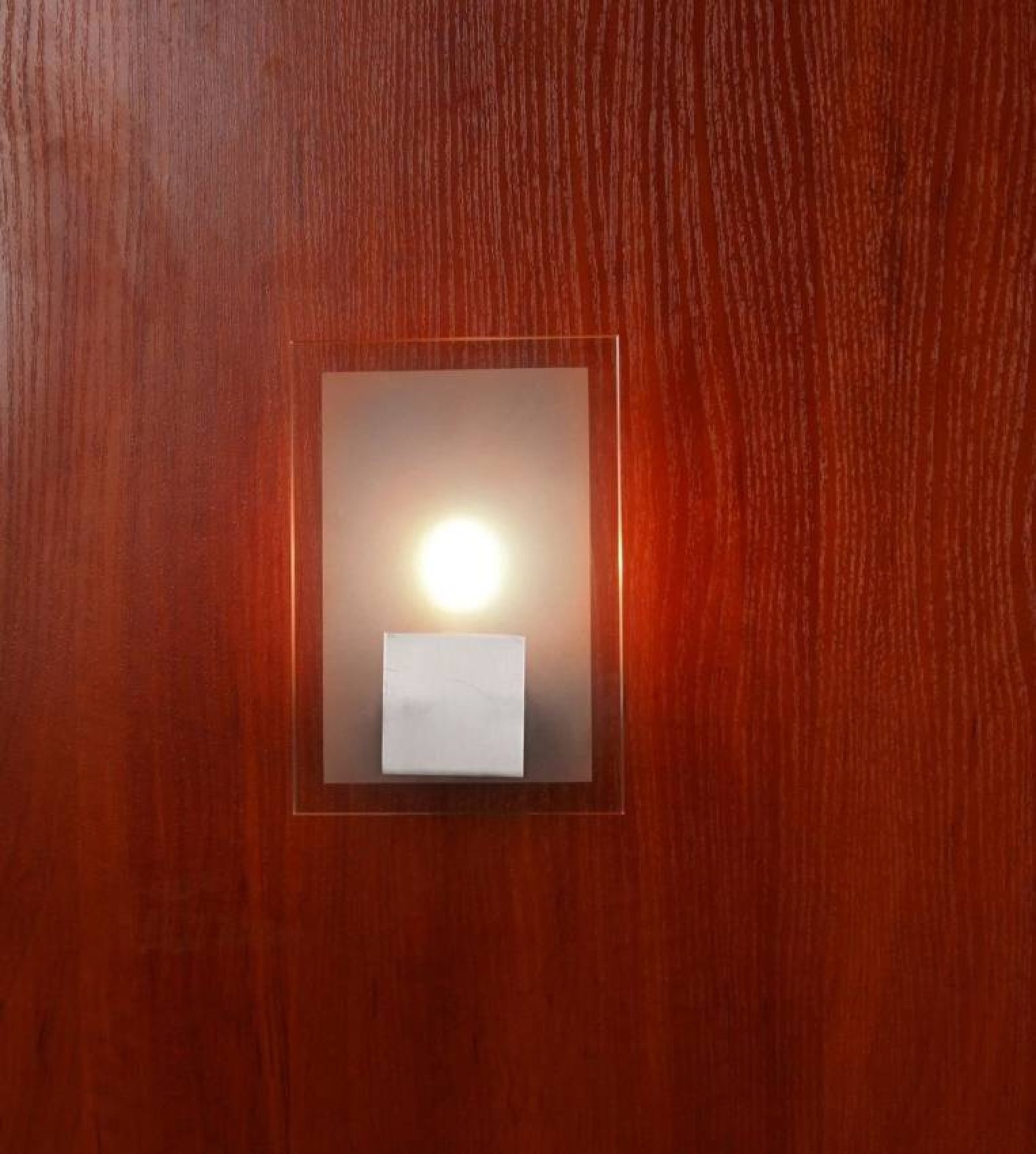 Kinkiet Alodela prostokątny świecący na drewnianej ścianie