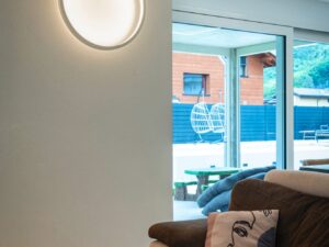 Miniaturka 7 - Biały kinkiet One 40 DALI świecący nad sofą w salonie