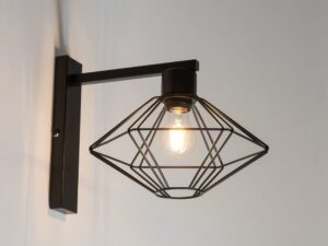 Miniaturka 1 - Czarny kinkiet Vario z zapaloną żarówką wewnątrz geometrycznego klosza na ścianie