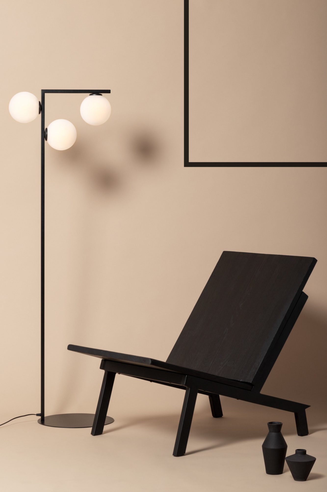 Czarna lampa podłogowa Andy obok fotela w nowoczesnym salonie