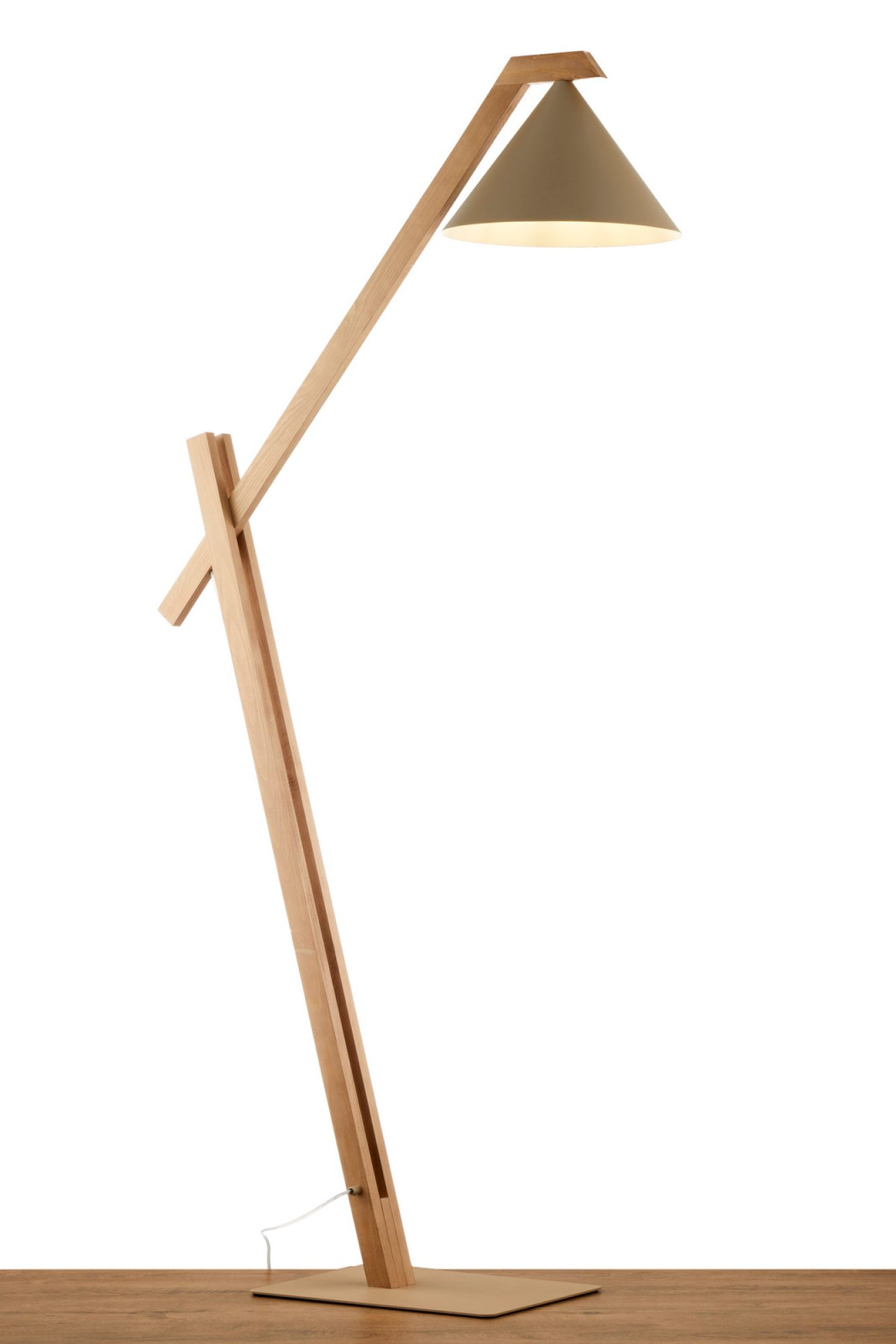 Lampa podłogowa Deco z beżowym kloszem zapalona przy ścianie