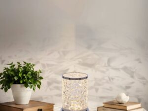 Miniaturka 1 - Lampa stołowa Ilvimano 14,5 cm świecąca na komodzie obok książek