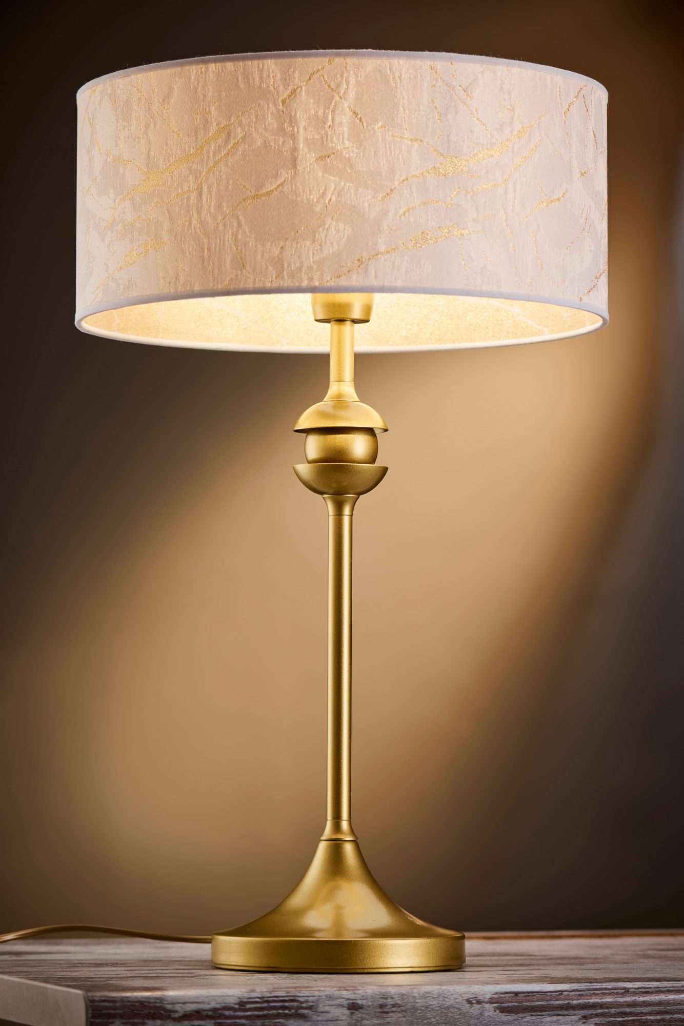 Lampa stołowa Kaszmir złota z jasnym zdobionym abażurem, zapalona