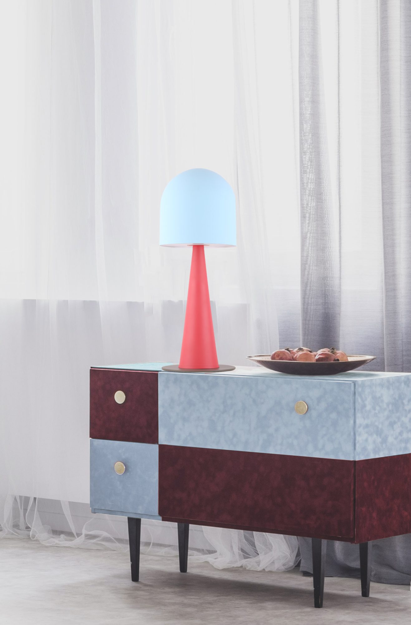 Lampa stołowa Nerivio w błękicie i czerwieni ustawiona na komodzie