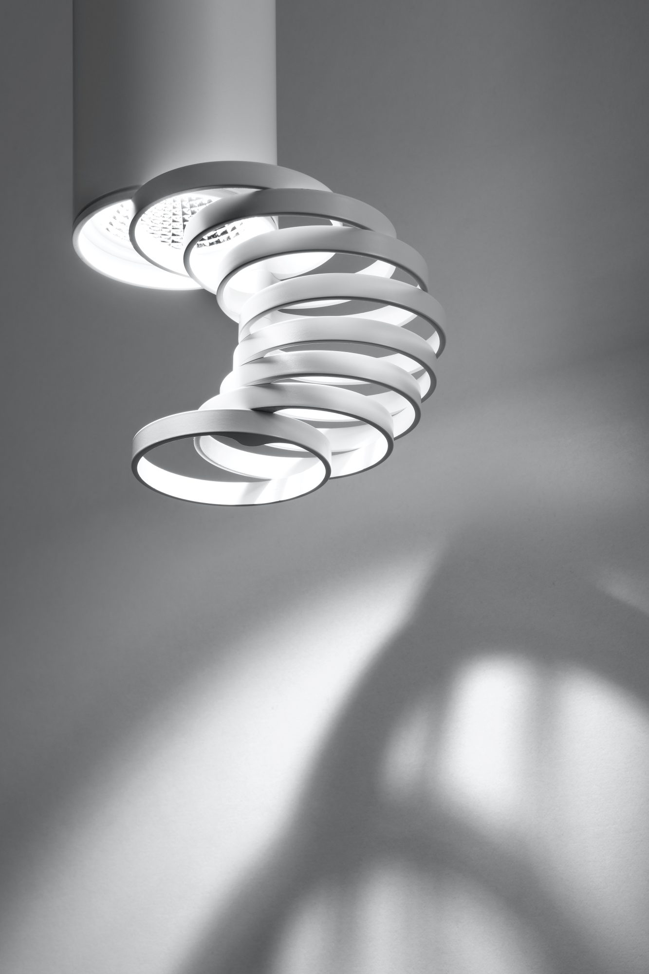 Detal białej lampy sufitowej GU10 z odchylonym spiralnym elementem świetlnym