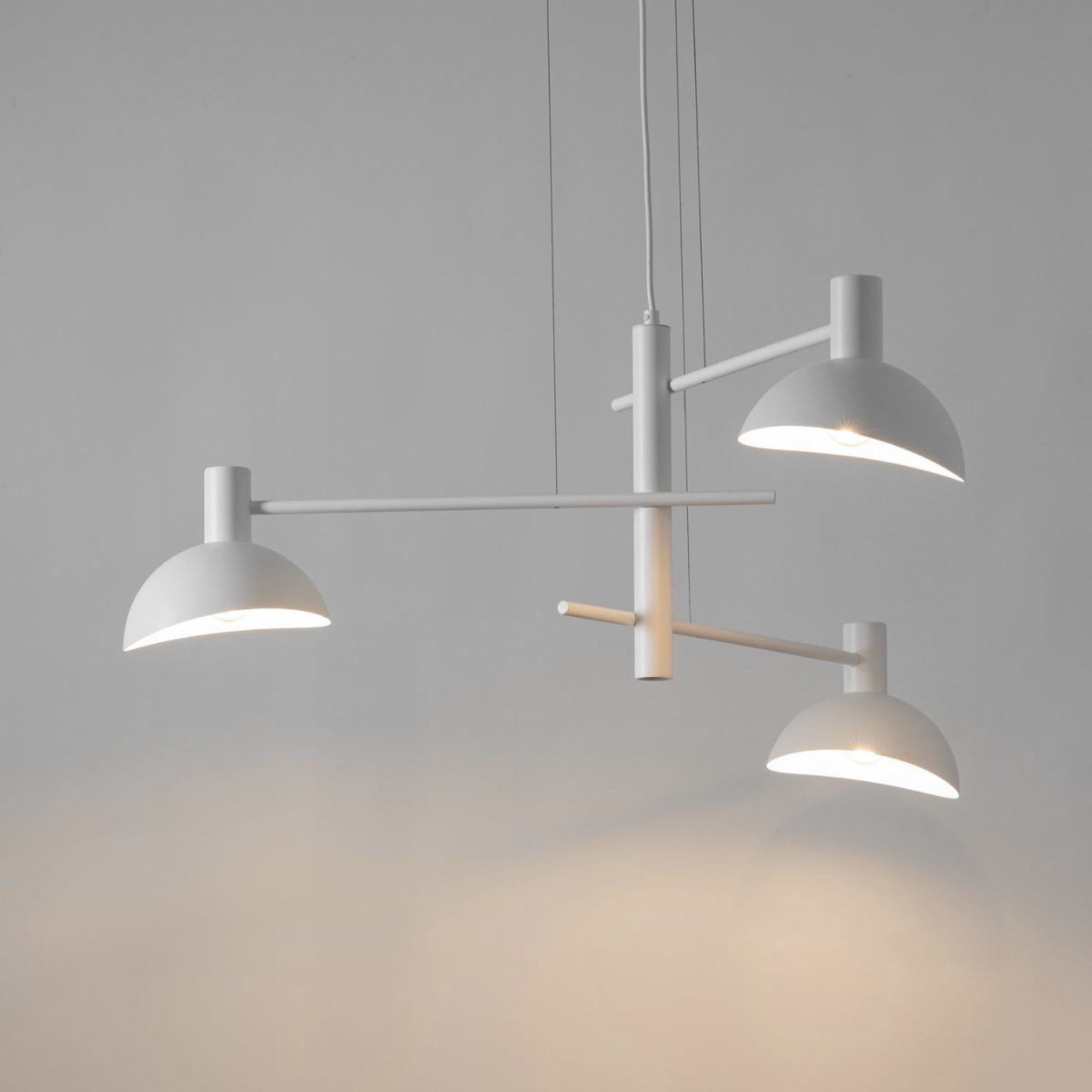 Biała lampa wisząca Artis 3 z zapalonymi trzema źródłami światła
