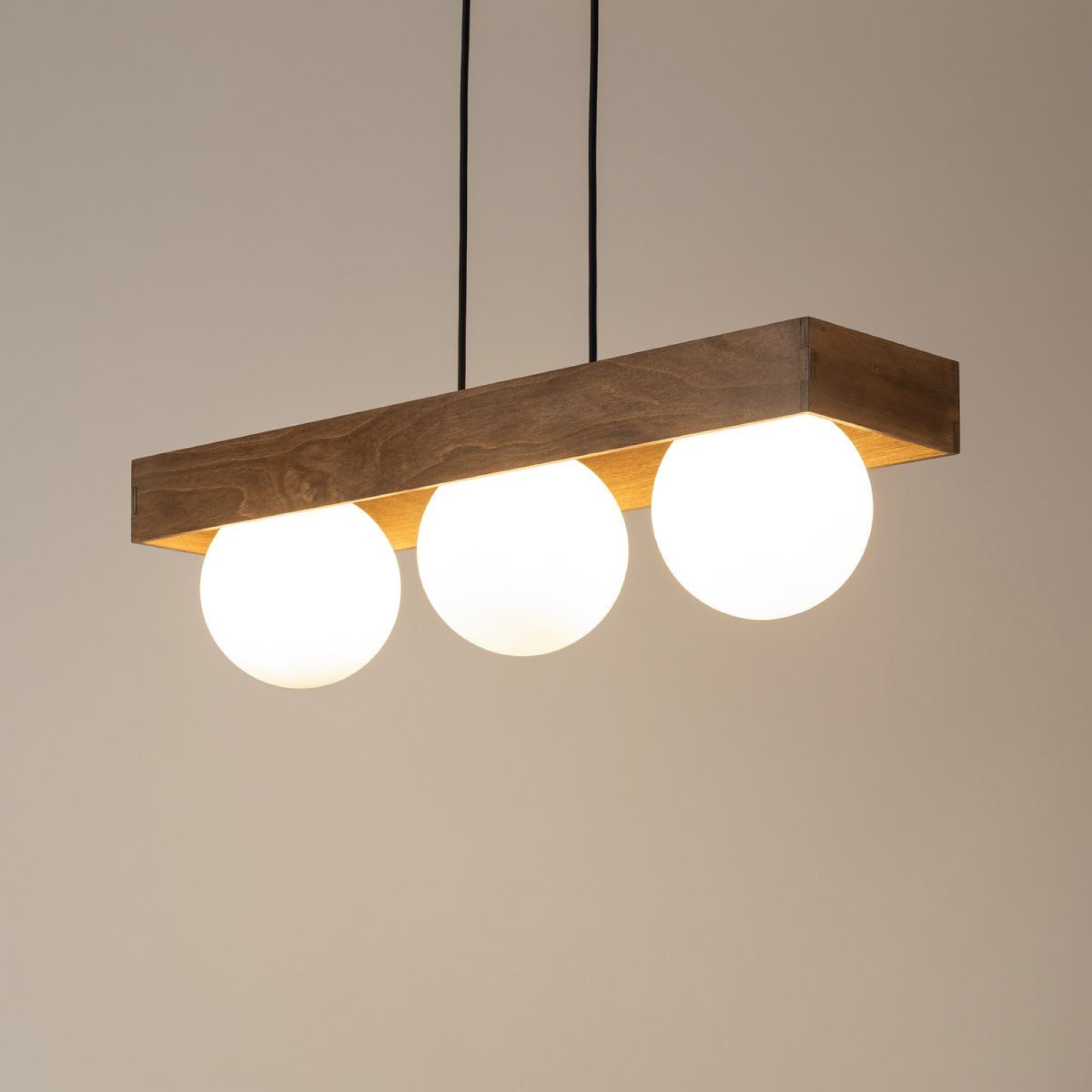 Lampa wisząca Bloom 3 z trzema rozświetlonymi białymi kulami pod brązową belką