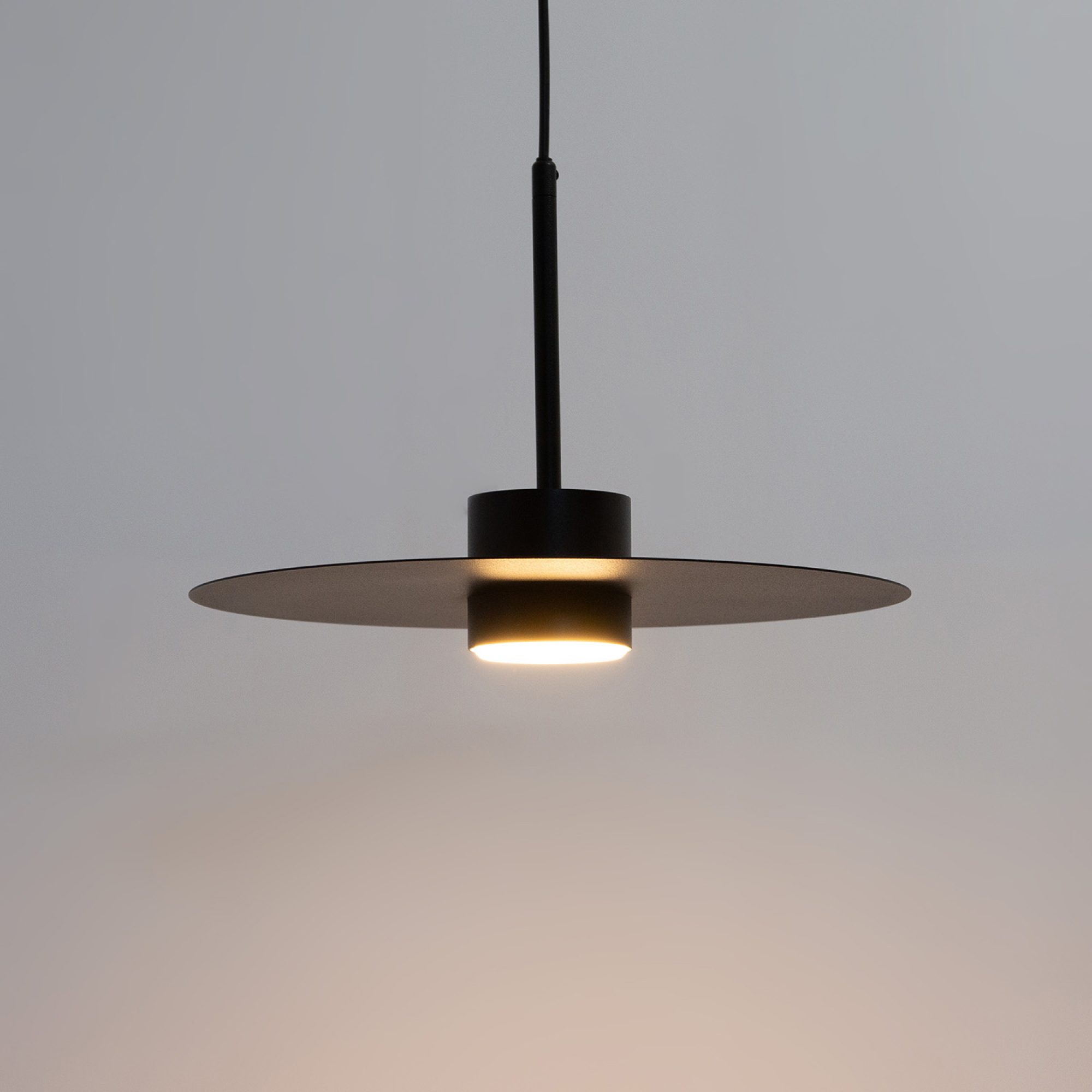 Czarna lampa Charlie L ze świecącą żarówką GX53 na jasnym tle