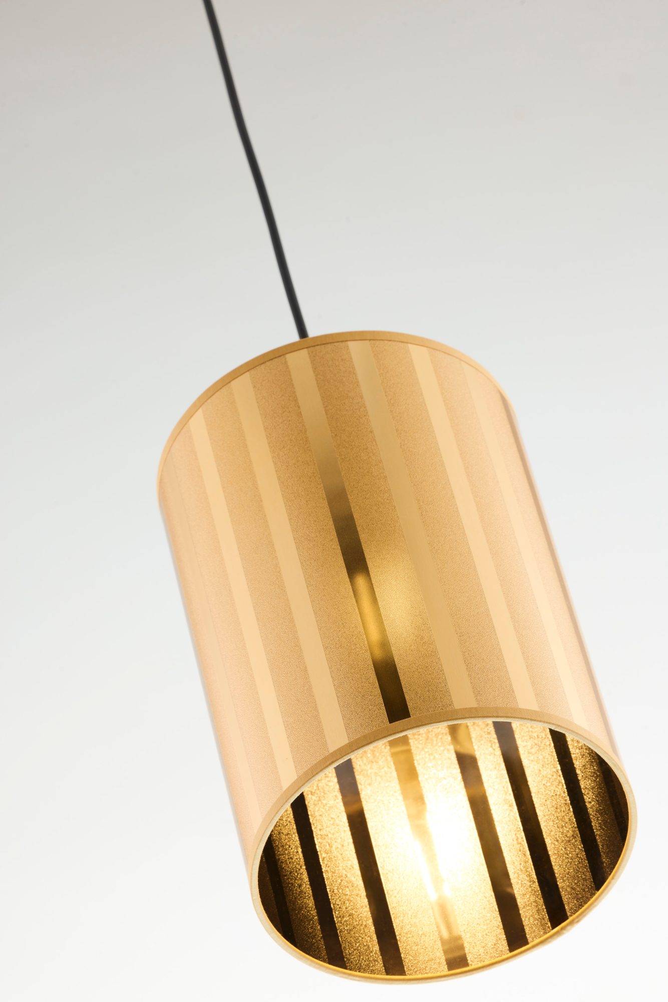 Lampa Cortina ze złotym cylindrycznym kloszem z widocznym światłem wewnątrz
