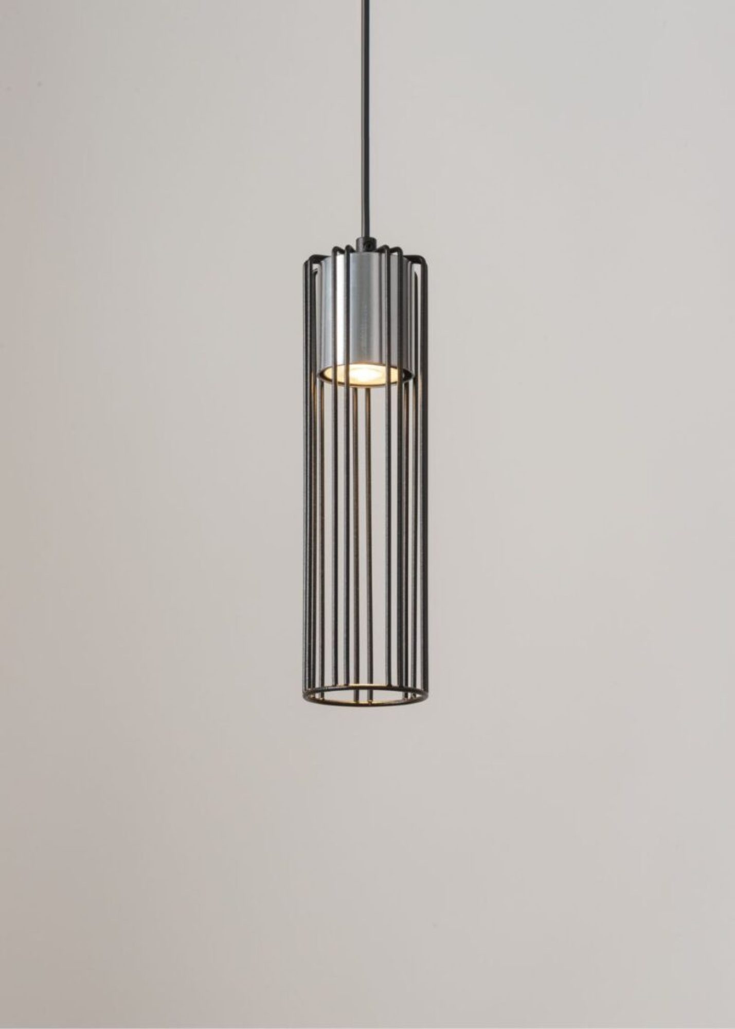 Lampa Fobia 1 z czarnymi prętami i srebrnym elementem przy zapalonym świetle