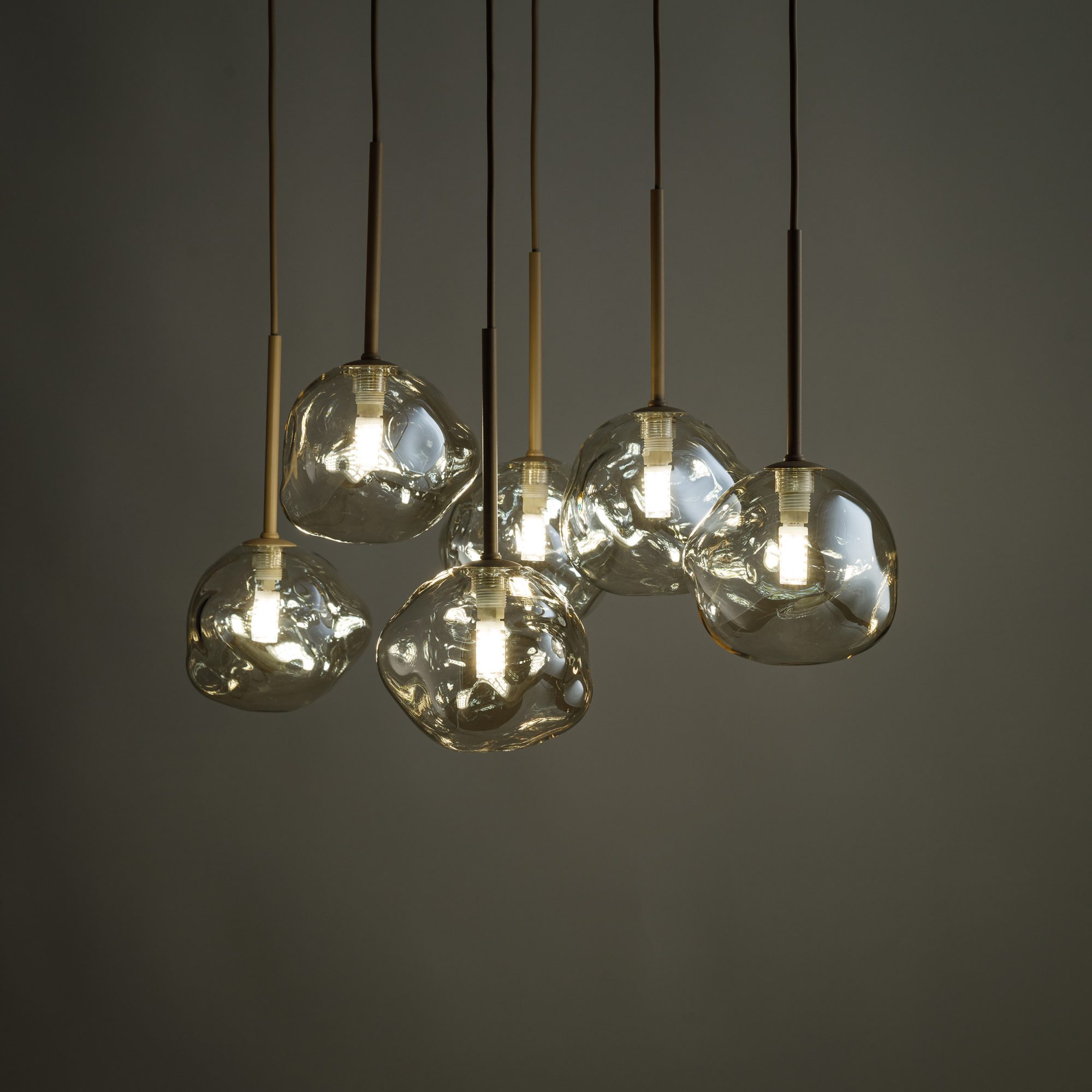 Lampa wisząca Lava w piaskowym beżu z koniakowymi kloszami podczas świecenia