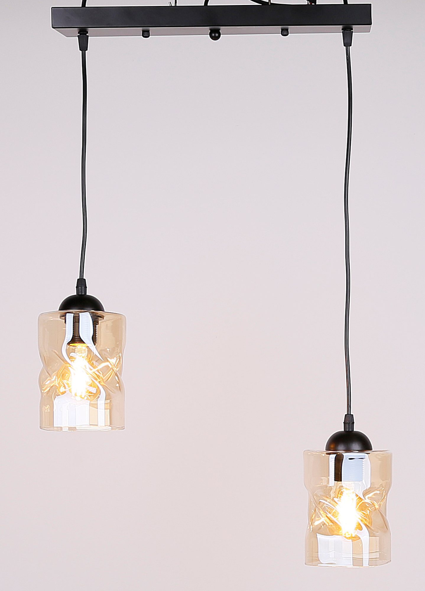 Lampa wisząca Norodira z podświetlonym bursztynowym szkłem na jasnym tle
