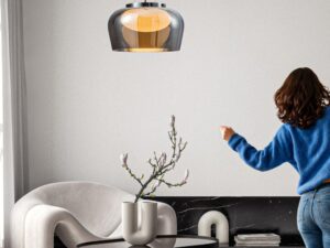 Miniaturka 2 - Lampa wisząca Novemora nad stolikiem w salonie z przydymionym szklanym kloszem