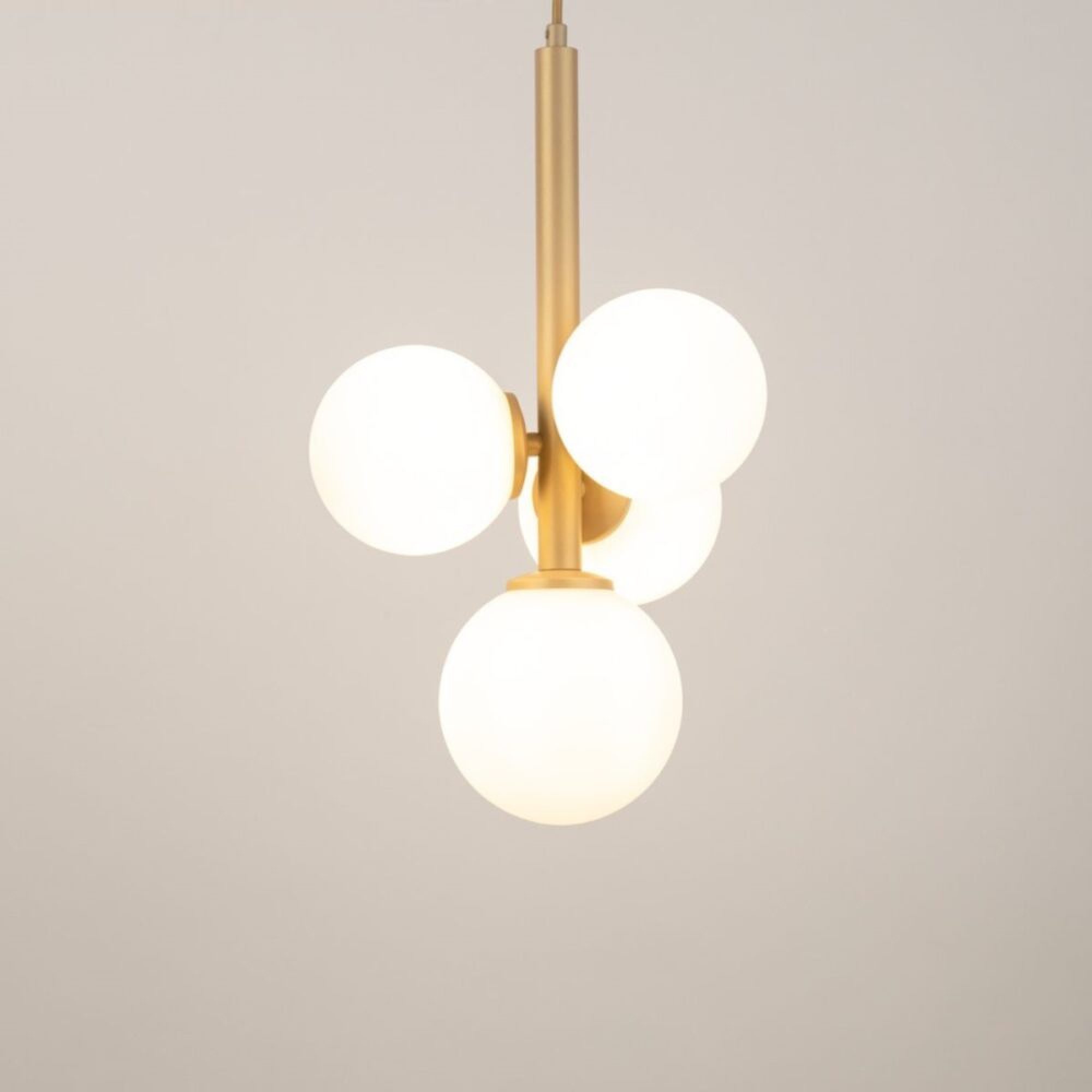 Lampa wisząca Perla 4 złoty beż z czterema świecącymi białymi kloszami w aranżacji