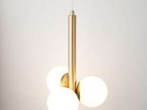 Miniaturka 1 - Lampa wisząca Perla Lux 3, białe szklane kule rozświetlone wokół złotego pionowego korpusu.