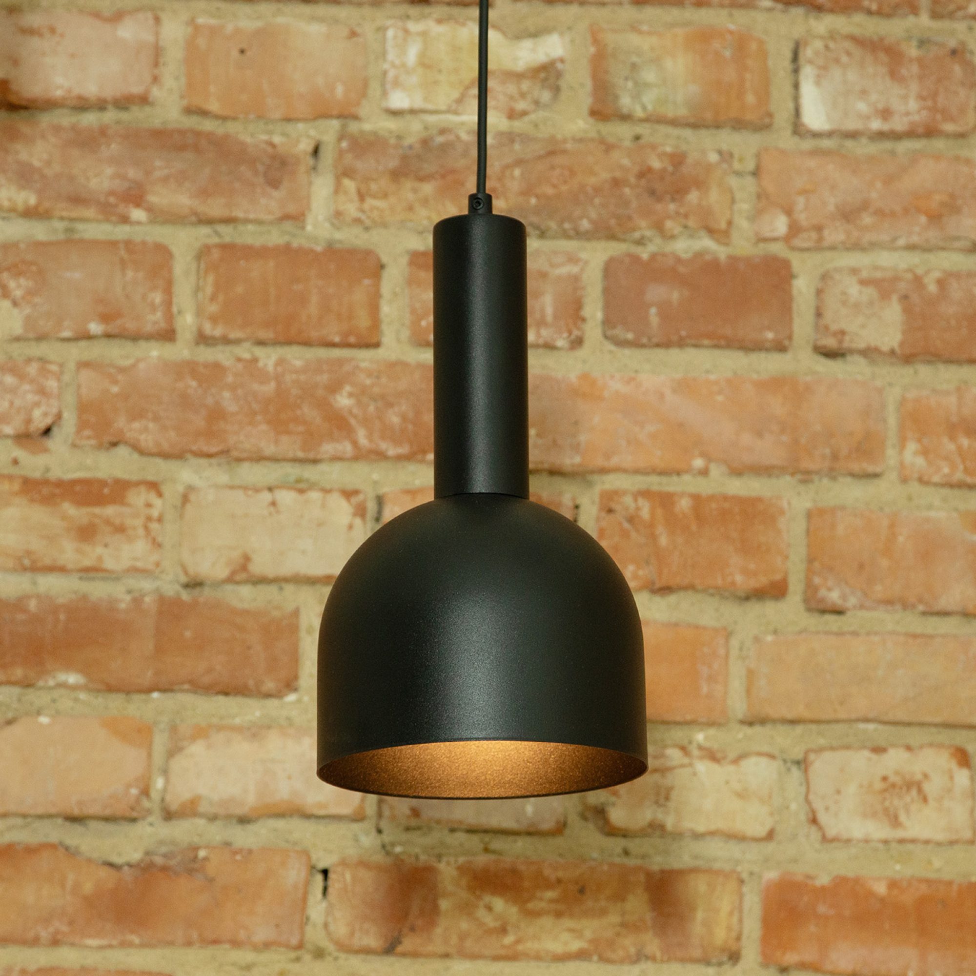 Czarna lampa wisząca Vitrum Dzwonek na tle ceglanej ściany