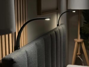 Miniaturka 1 - Czarna lampka LED zamocowana przy zagłówku łóżka tapicerowanego, światło do czytania