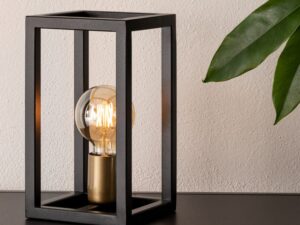 Miniaturka 1 - Lampka stołowa Vigo czarno-złota na półce przy jasnej ścianie i zielonej roślinie