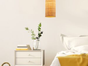 Miniaturka 1 - Lampa wisząca Peravina z rattanowym cylindrem przy łóżku w jasnej sypialni